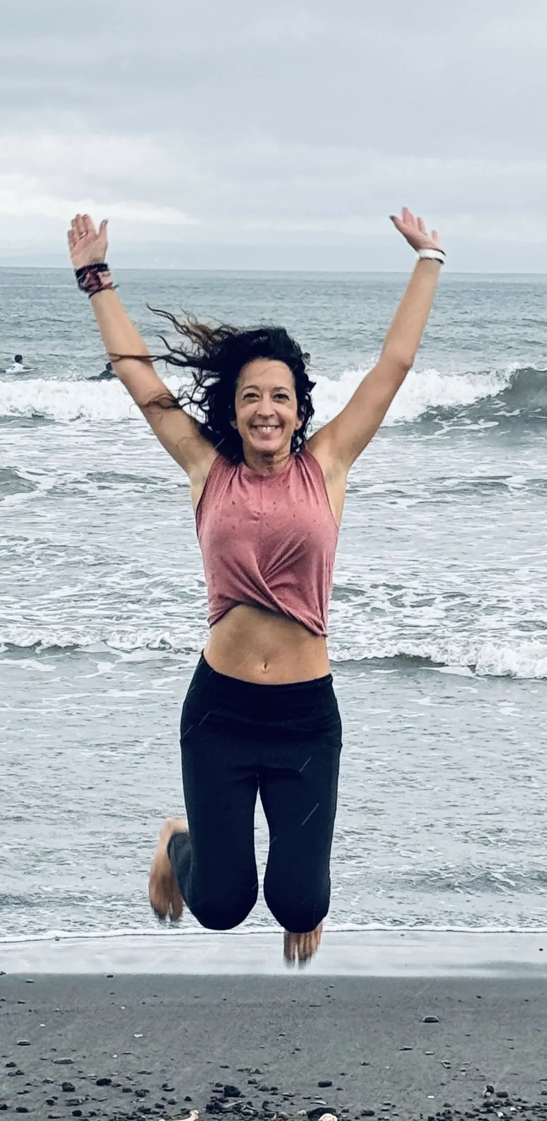 Alexandra Berna sautant sur la plage, bras levés — joie retrouvée