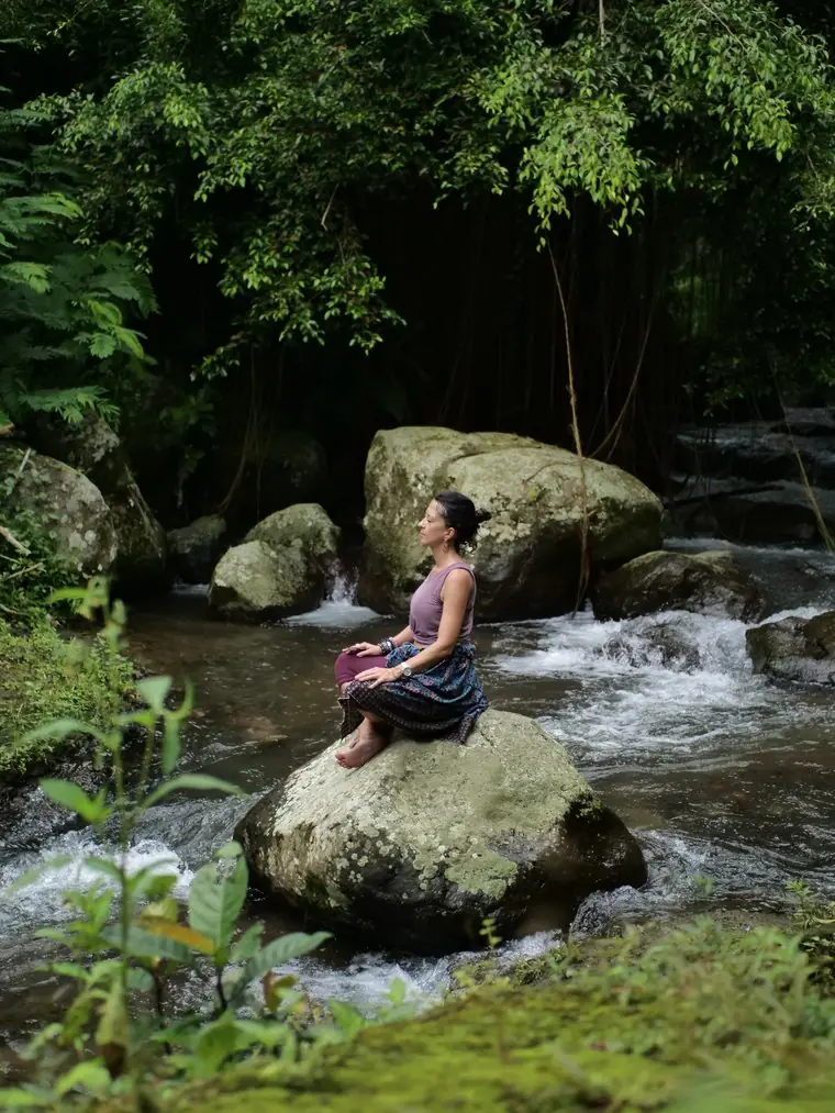 Alexandra en méditation sur un rocher au cœur de la rivière