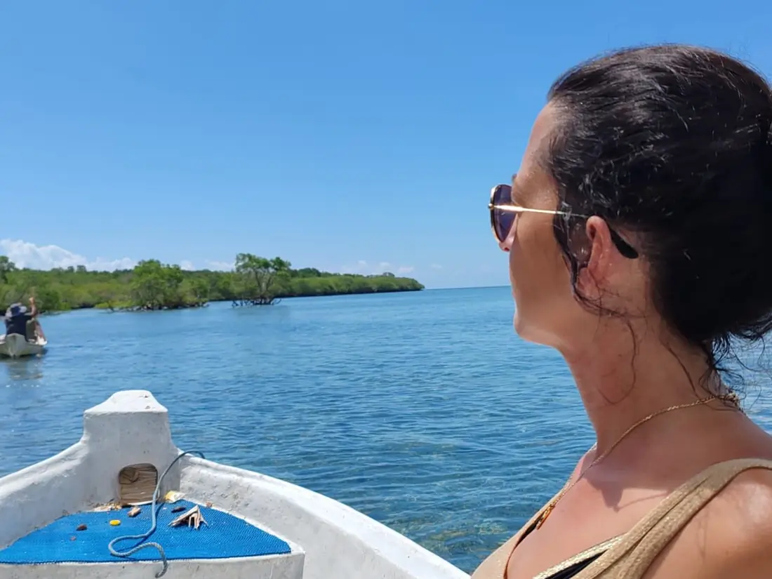 Alexandra sur un bateau, à l'horizon des mangroves — le départ