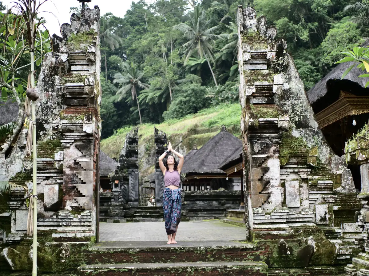 Alexandra devant un temple balinais, bras levés vers le ciel